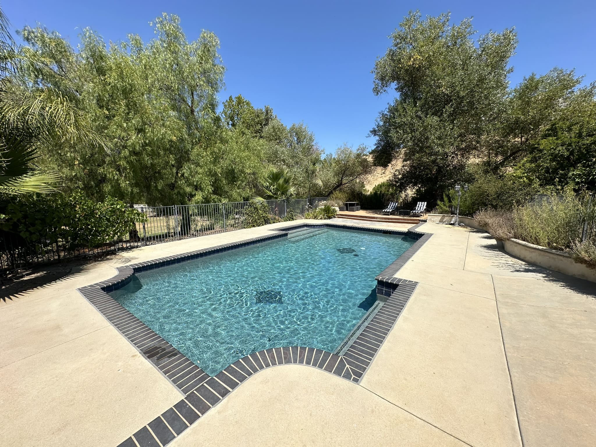 A pool with a large stone wall and a blue swimming pool.